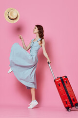 Wall Mural - cheerful woman tourist red suitcase hat travel pink background