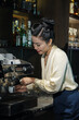 © DragonImages - Elegant female restaurant owner making herself cup of espesso in coffee maker