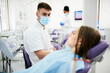© Drazen - Young dentist communicating with patient before dental exam at dentist's office.