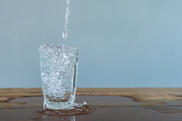 water pouring into glass on wooden table outdoors