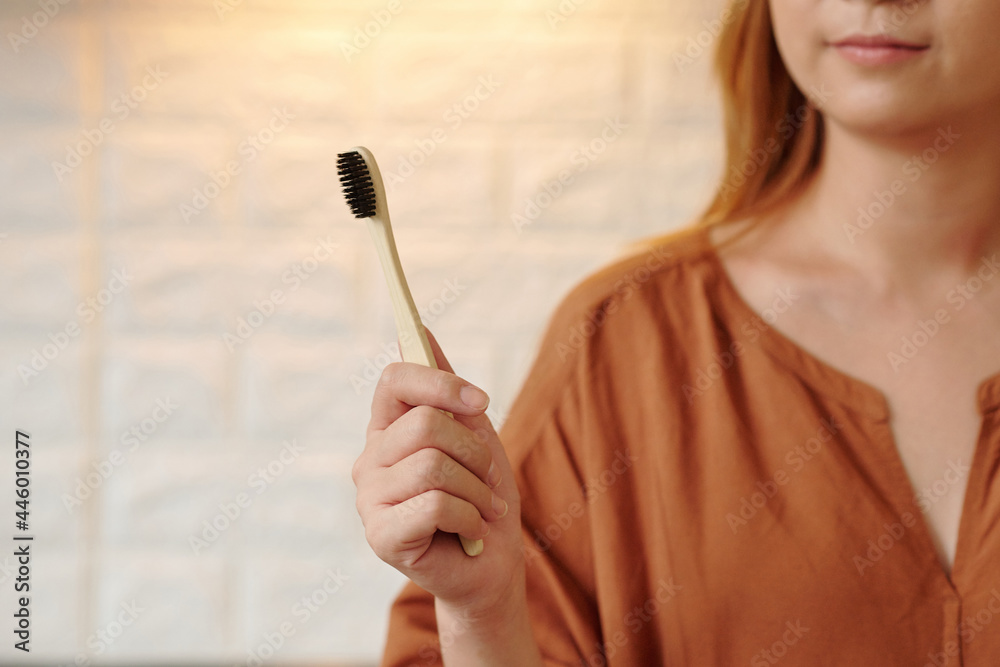 Young woman showing environmentally friendly wooden toothbrush - obrazy, fototapety, plakaty 