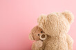 Brown teddy bear mother hugging her baby on light pink background. Lovely, emotional moment. Closeup. Copy space. Empty place for emotional text, cute quote or sayings.