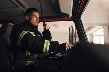 Wall Mural - Firefighter using radio set while driving fire truck