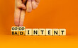 Good or bad intent symbol. Businessman turns wooden cubes and changes words 'bad intent' to 'good intent'. Beautiful orange table, orange background. Business, bad or good intent concept. Copy space.