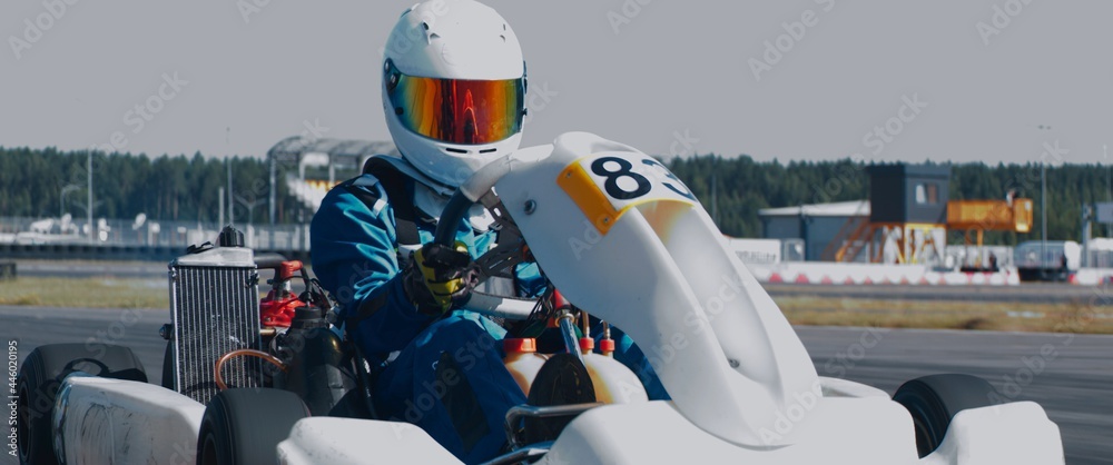 Front view of teenager professional racer driving his go kart on a race track. Shot with 2x anamorphic lens - obrazy, fototapety, plakaty 