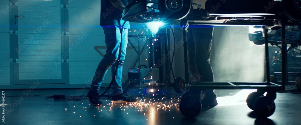 CU Sparks falling on the ground as mechanic welding a go kart car inside garage - obrazy, fototapety, plakaty 