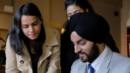 Young Indian businessman with a turban discussing a project with two workers during the meeting