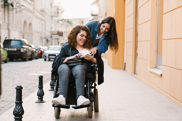 Young two women smiling and using mobile phone at city street