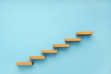 Wall Mural - Wooden staircase on blue background. Growth, increasing business, success process concept. Copy space