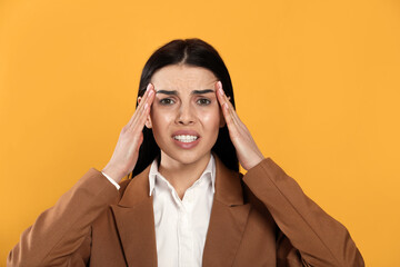 Wall Mural - Woman suffering from migraine on yellow background