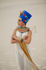 Wall Mural - Woman in image of egyptian queen Nefertiti stands in desert with whip.