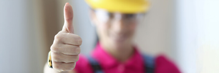 Woman in safety helmet showing thumb up closeup