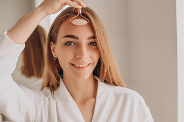 Wall Mural - Woman doing self massage with rose quartz face roller