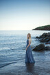 © Berzyk - beautiful girl in a gray dress by the sea at sunset