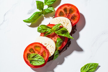 Canvas Print - Caprese sandwich on white marble background. Toast with mozzarella, tomato and basil.