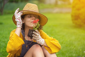 Wall Mural - A young woman gardener is holding a petunia flower in a peat pot