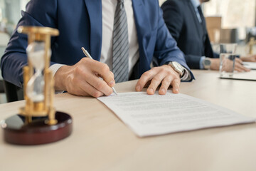 Aufkleber - Close-up of businessman sitting at the table and signing a contract during a business meeting at office