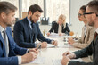 © pressmaster - Group of business people sitting at the table and making notes at the table during a business meeting at office