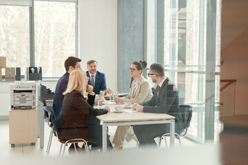 Canvas Print - Group of business people sitting at the table and discussing together during business meeting at office