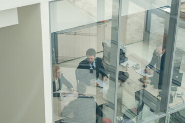 Poster - Group of business people working together during a meeting behind window at modern office