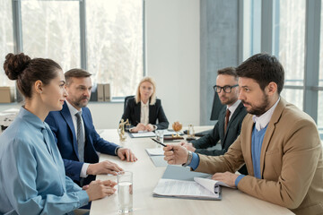 Poster - Group of business people sitting at the table and discussing work during teamwork at meeting