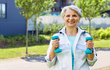 Sticker - fitness, sport and healthy lifestyle concept - happy smiling senior woman with dumbbells exercising over city street background