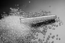 White Granules Of Rubber And Polypropylene On A Black Background In A Chemical Test Tube. Plastics And Polymers Industry.