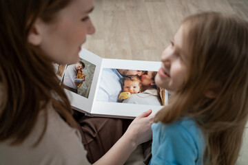 mother and daughter looking a book with photos from a family photo shoot