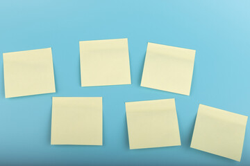 Wall Mural - yellow sticky notes on blue background. Square sticky paper reminders with shadows