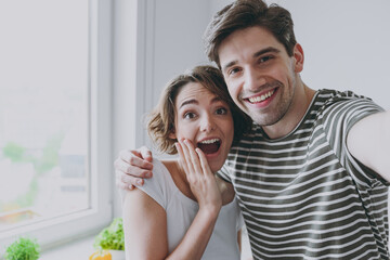 Wall Mural - Close up young happy surpise couple two woman man 20s in casual tshirt clothes hug spend time together do selfie by mobile cell phone cook food in light kitchen at home Healthy diet lifestyle concept