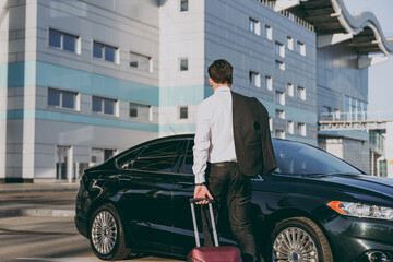 Wall Mural - Bottom back rear view young traveler businessman young man wearing black dinner suit walk go outside at international airport terminal with suitcase to car book taxi Air flight business trip concept