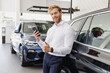 Man smiling customer male buyer client in white shirt talk mobile cell phone show thumb up choose auto want buy new car automobile in showroom vehicle dealership store motor show indoor Sales concept.