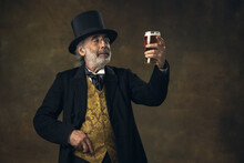 Elderly Gray-haired Man, Gentleman, Aristocrat Or Actor Drinking Beer Isolated On Dark Vintage Background. Retro Style, Comparison Of Eras Concept.