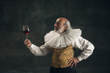 Elderly Gray-haired Man, Medieval Hystorical Person, Actor Drinking Wine Isolated On Dark Vintage Background. Retro Style, Comparison Of Eras Concept.