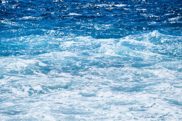 Wall Mural - Waves and blue water as a background. View at the ocean surface. Natural summer seascape. Water background. Abstract blue ocean background.