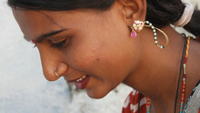 Portrait Of A Young Indian Female With Earrings And A Nose Piercing Looking Down With A Cute Smile