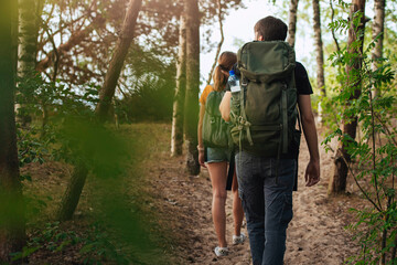 Male and female couple going outdoors backpacking, captured from behind