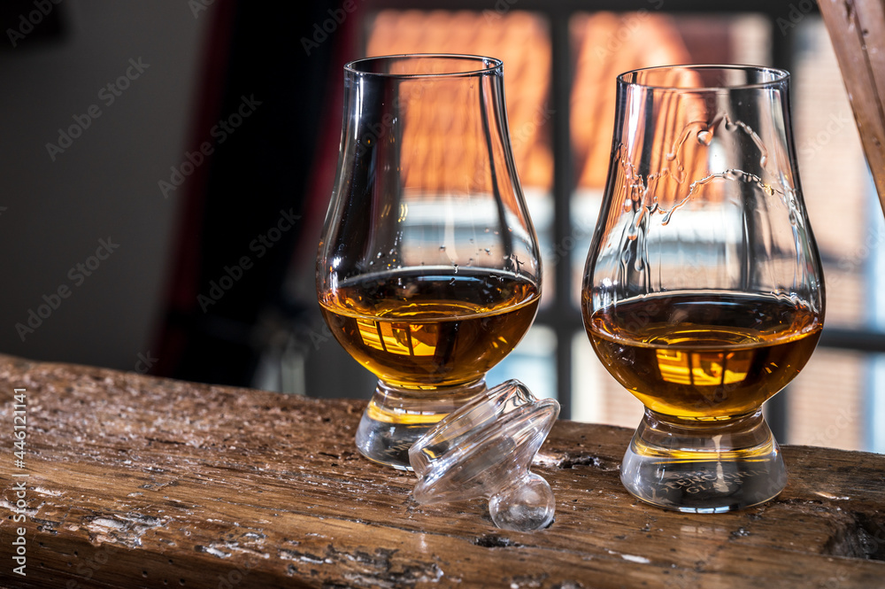Dram of single malt scotch whisky served in tasting glass with view on old window and houses - obrazy, fototapety, plakaty 