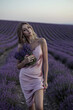 beautiful woman with blond hair in luxurious silk dress posing in blooming lavender field on sunset