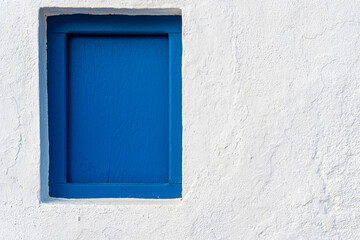 Small blue painted wooden window in a white wall.