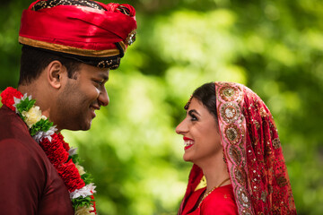Canvas Print - side view of happy indian bridegroom and bride looking at each other