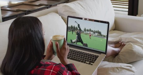 Canvas Print - Composite of woman sitting at home holding coffee watching hockey match on laptop