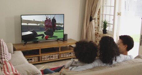 Wall Mural - Composite of happy family sitting at home together watching hockey match on tv