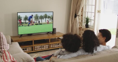 Canvas Print - Composite of happy family sitting at home together watching hockey match on tv