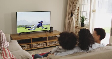 Wall Mural - Composite of happy family sitting at home together watching baseball game on tv