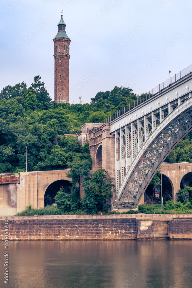 Bronx, NY - USA - July 17, 2021: Vertical view of the historic High Bridge spanning the Harlem River and Highbridge Water Tower is the distance.