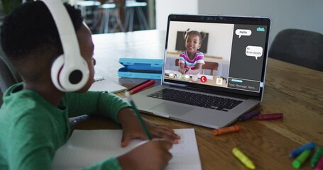 Canvas Print - Schoolboy using laptop for online lesson at home, with school friend and web chat on screen