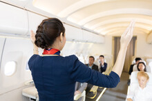 Back View Flight Attendant Giving Instructions Or Demonstrating About The Use Of Doors And Operations In Airplane