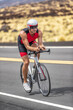 © Maridav - Triathlon time trial cycling triathlete man wearing aero bike helmet with visor biking on competition race day riding road bicycle vertical shot.