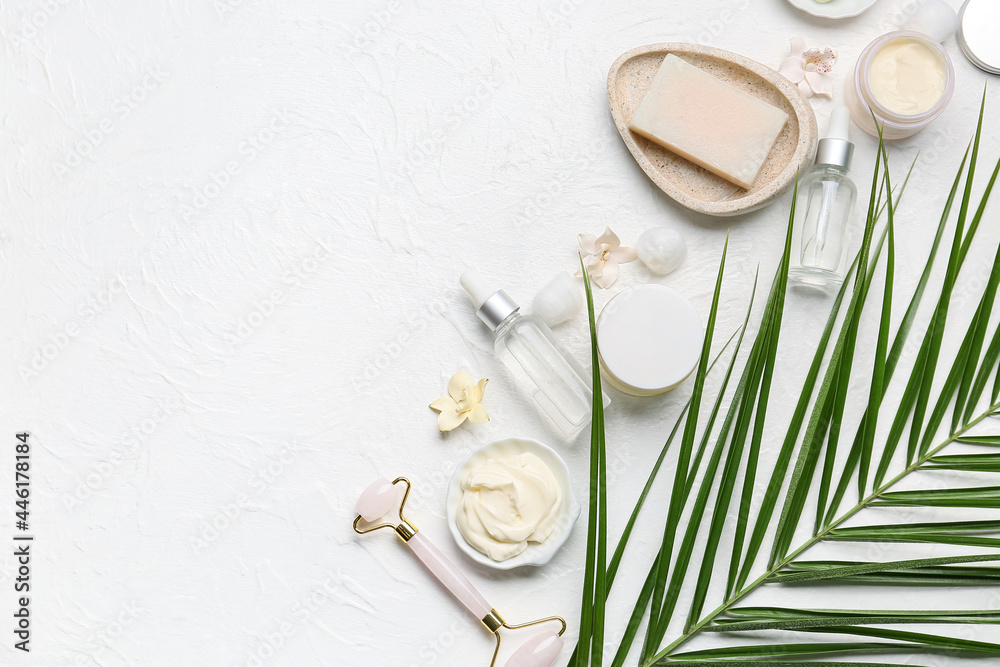 Set of bath supplies and palm leaf on light background